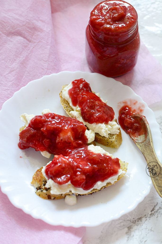 Three pieces of toast on a white plate. Each toast has ricotta cheese and Strawberry Rhubarb Sauce on top.