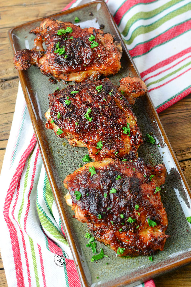 Air fryer chicken thighs sitting on a green plate ready to be served.