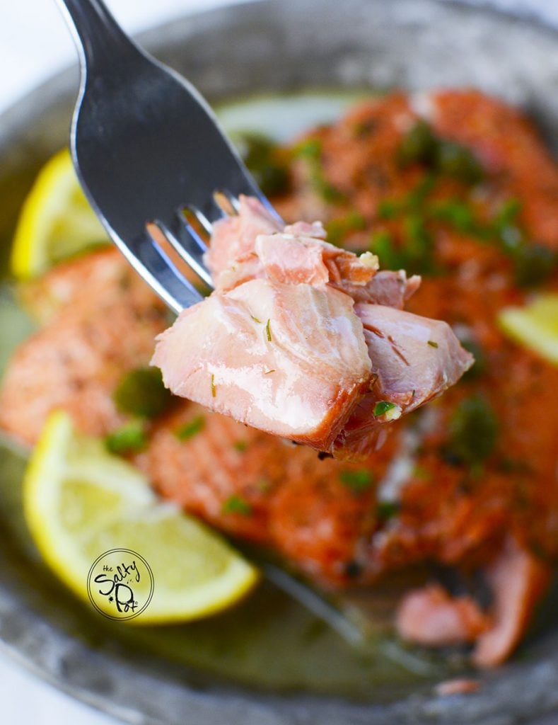 A bite size portion of juicy salmon on a fork.