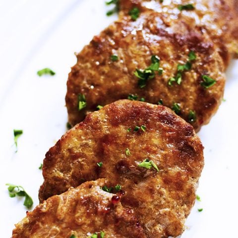 4 air fried sausage patties lined up on a white platter.