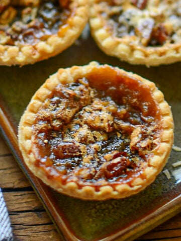 One butter tart shown close up with two other ones in the background at the top.