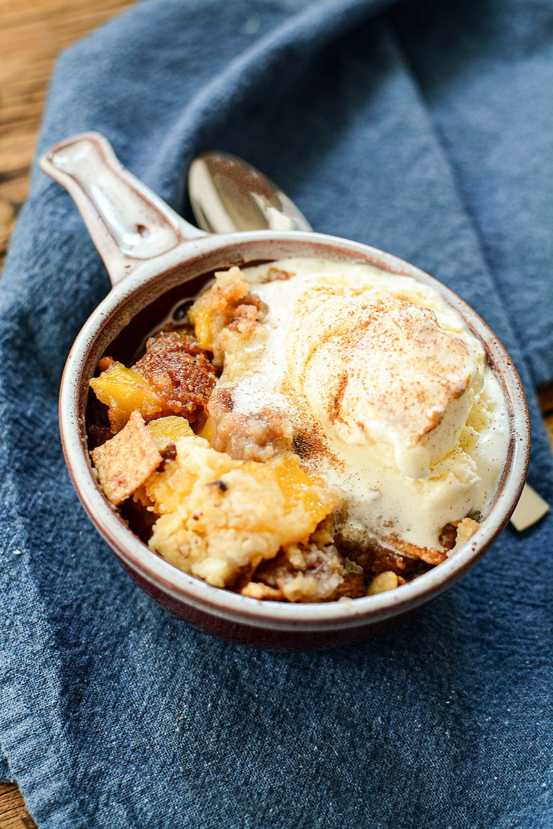 A picture of this peach cobbler made the second way, served in a bowl with a handle, and a scoop of ice cream over the top.