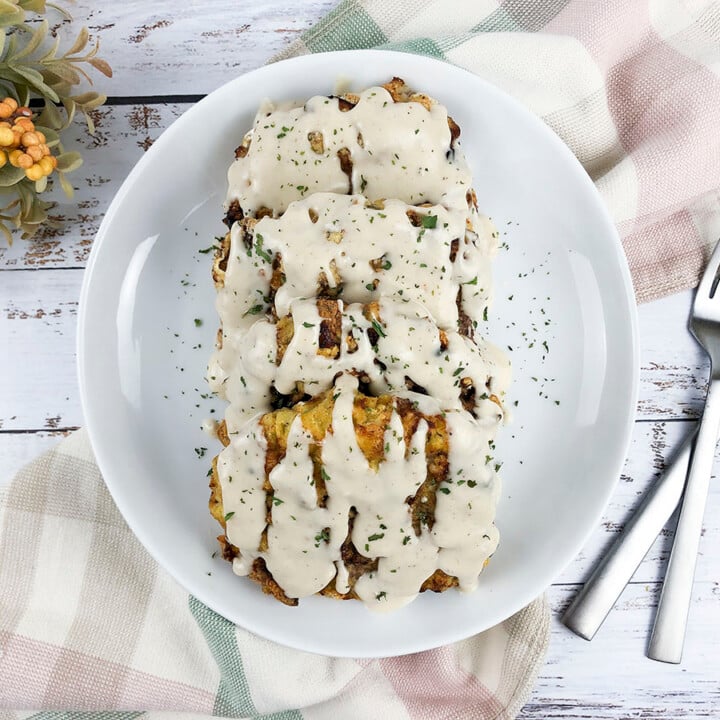 3 peices of delicious air fryer chicken fried steak on a white plate, with gravy poured over top.