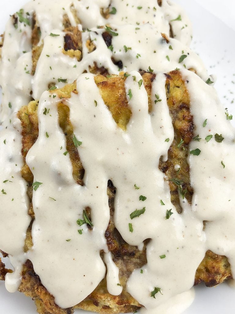 A close up of the chicken fried steak with gravy over the top.