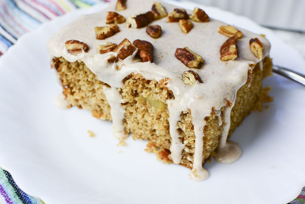 A piece of apple cake is sitting on a white plate.