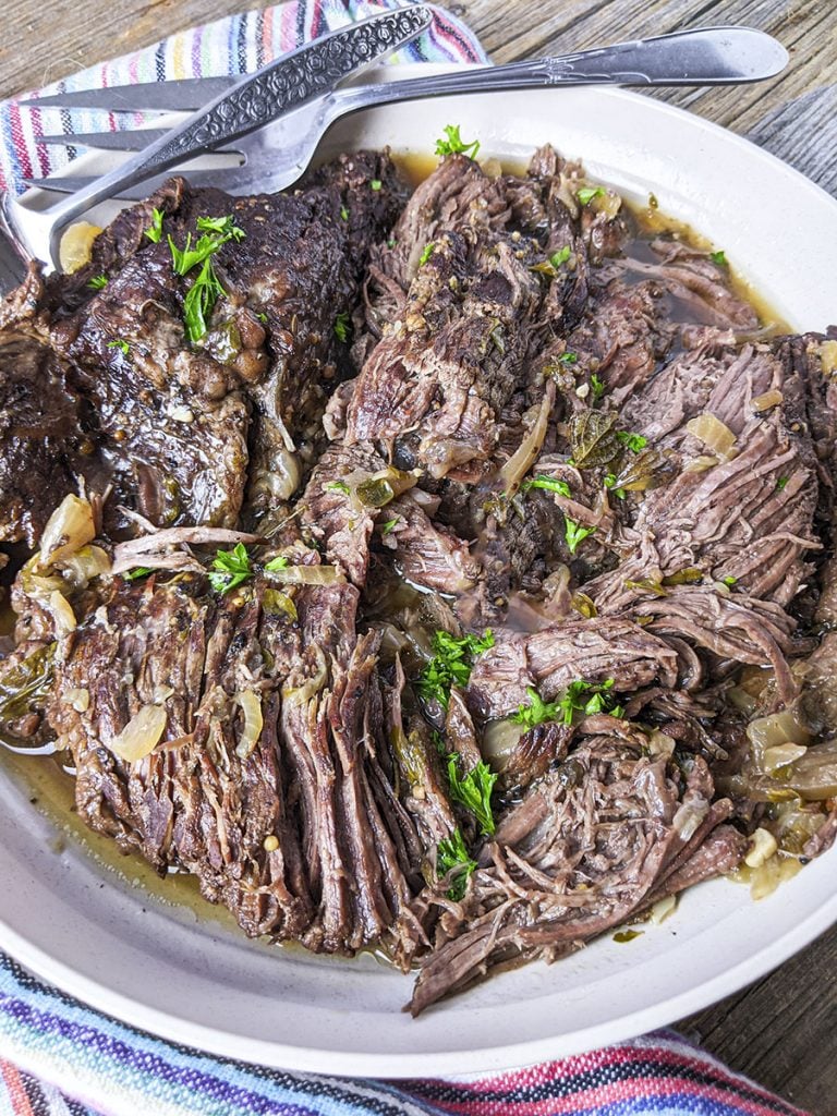 A top down photo of the pressure cooked beef with a serving fork laying on the plate at the top.