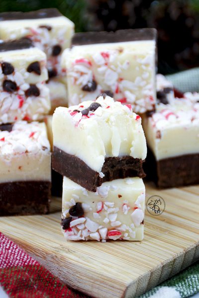 Squares of peppermint fudge sitting on a wooden cutting board.