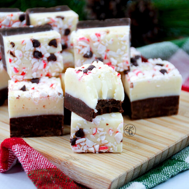 Squares of peppermint fudge sitting on a wooden cutting board.