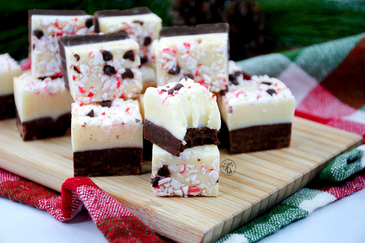 Squares of peppermint fudge sitting on a wooden cutting board.