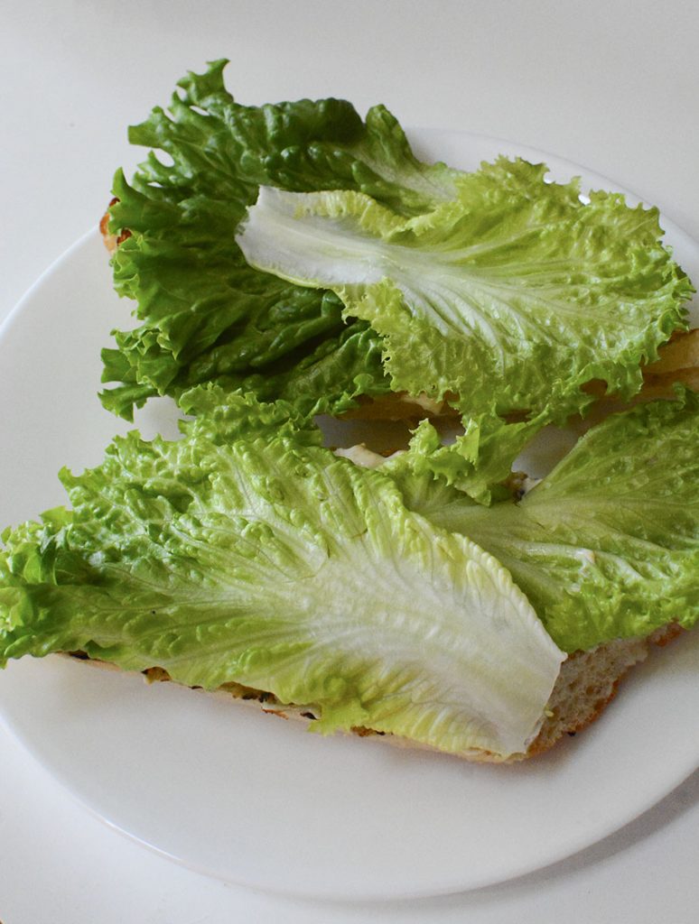 Romaine lettuce is placed over top the bread halves.