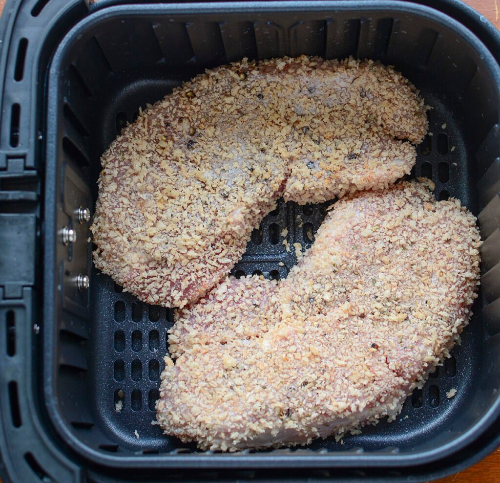 Raw, breaded pork steaks in the air fryer. 