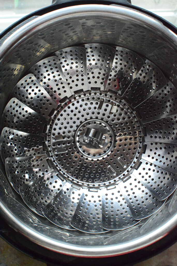 A steamer is added to the inside pot of the pressure cooker.