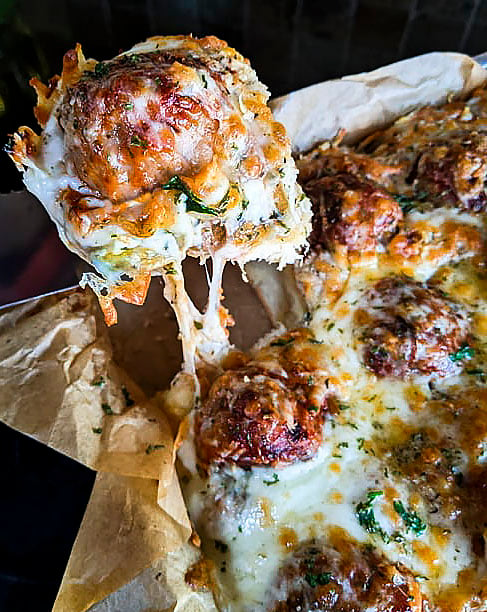 A meatball slider being lifted away from the rest of the sliders.