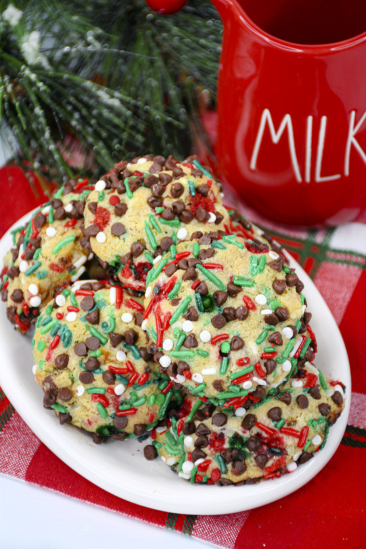 Decorated cookies are piled on top of eachother on a white plate.