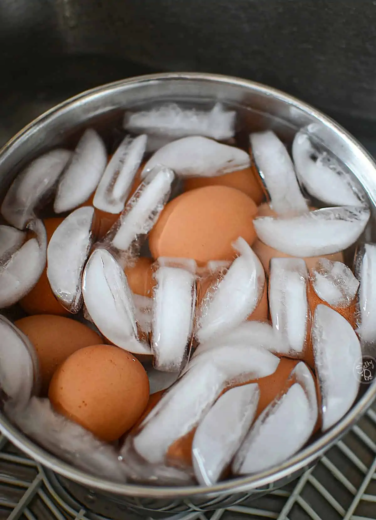 A dozen eggs sitting in iced water.