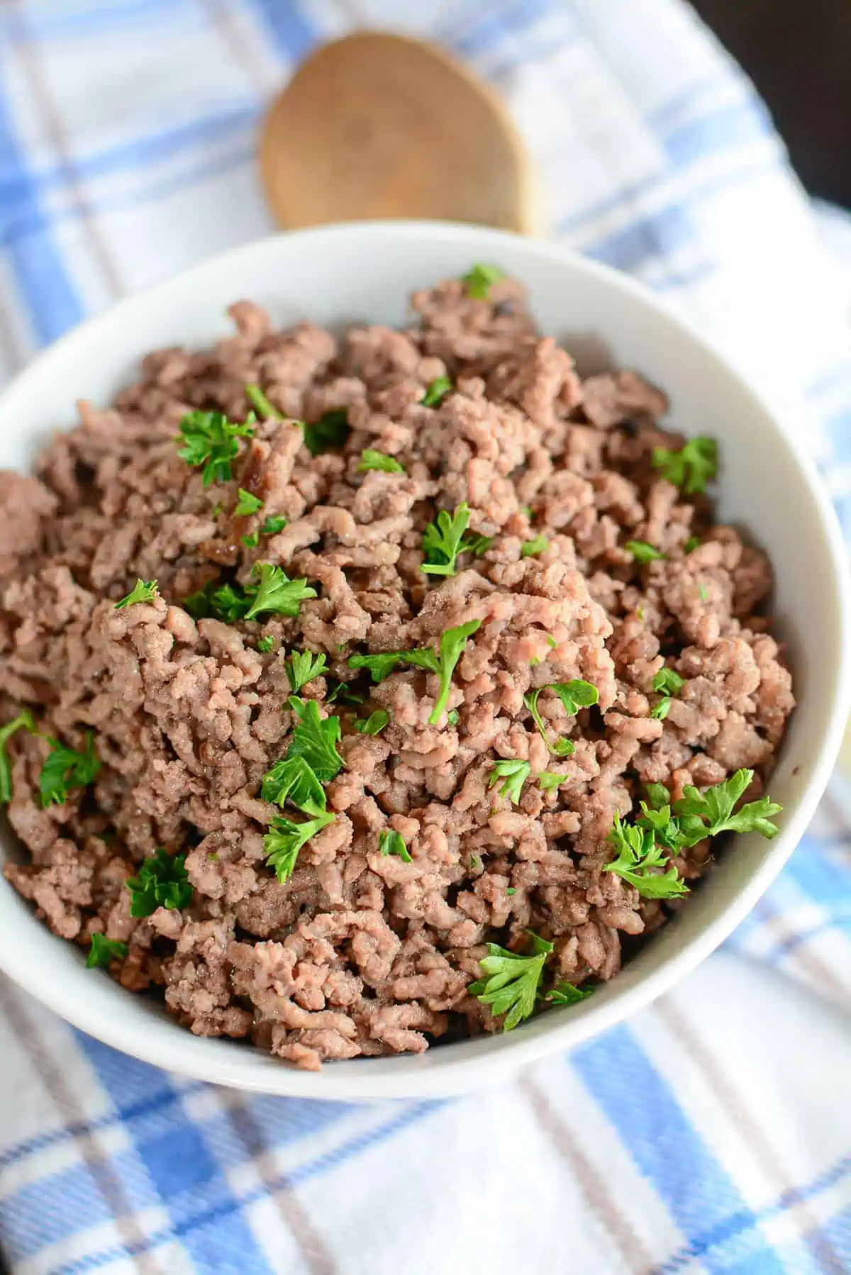 Cooked ground beef in a bowl with fresh parsley sprinkled over the top.