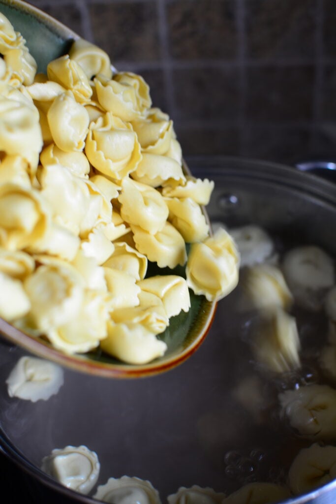 Tortellini falling into a pot of boiling water.