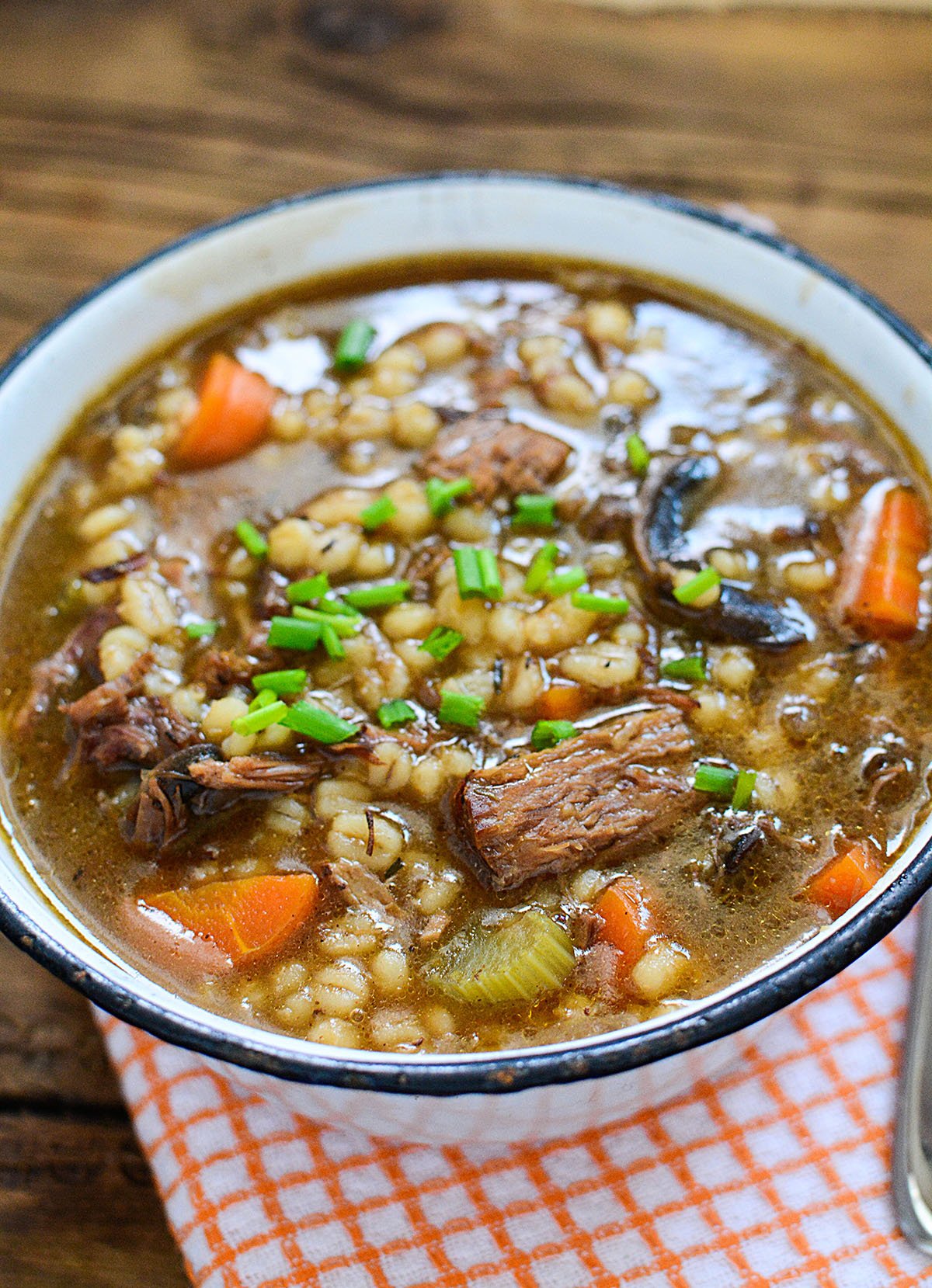 Stew with barley and other vegetables in a vintage white bowl with a black rim.