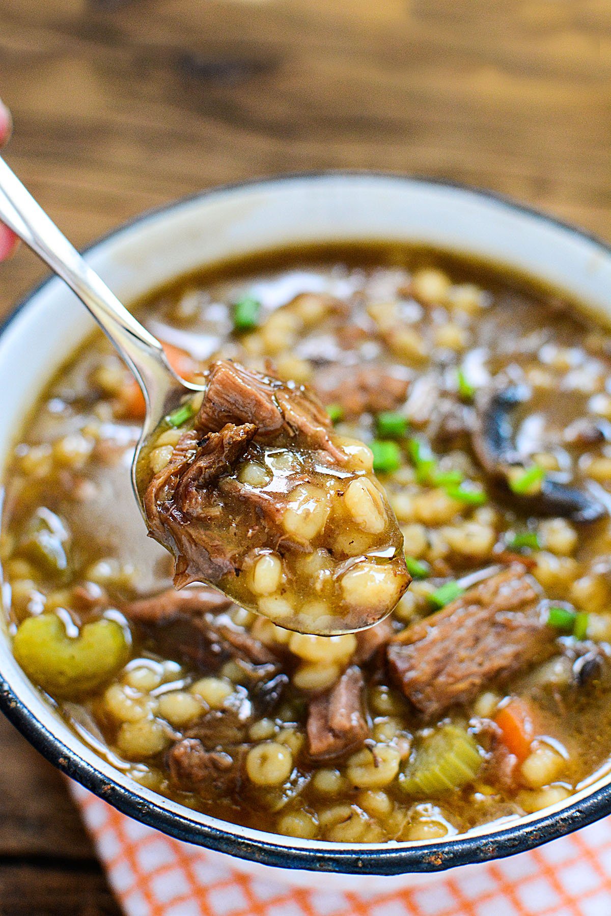 A spoonful of barley and beef with savory broth. 
