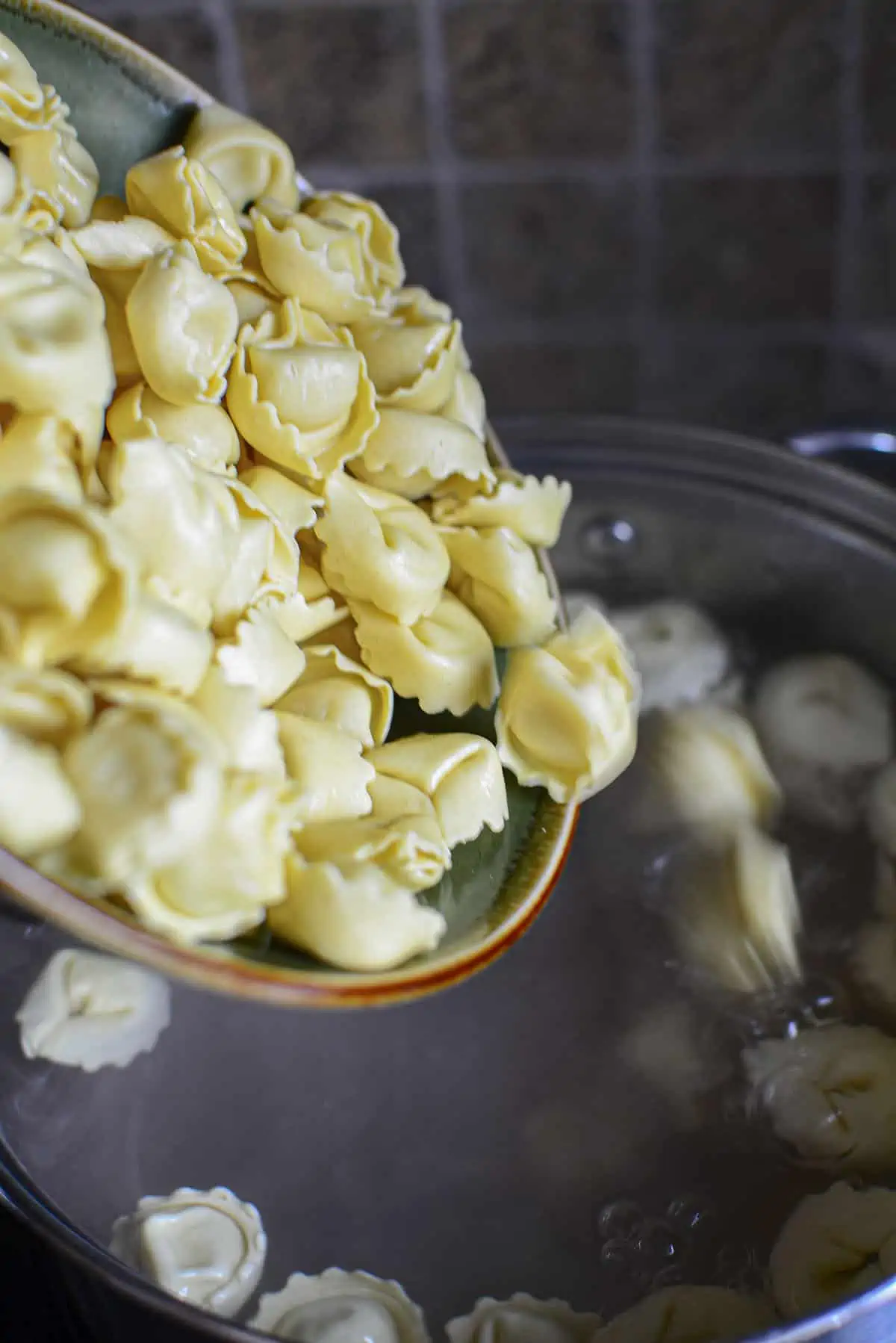 Gently dumping the tortellini into boiling water.