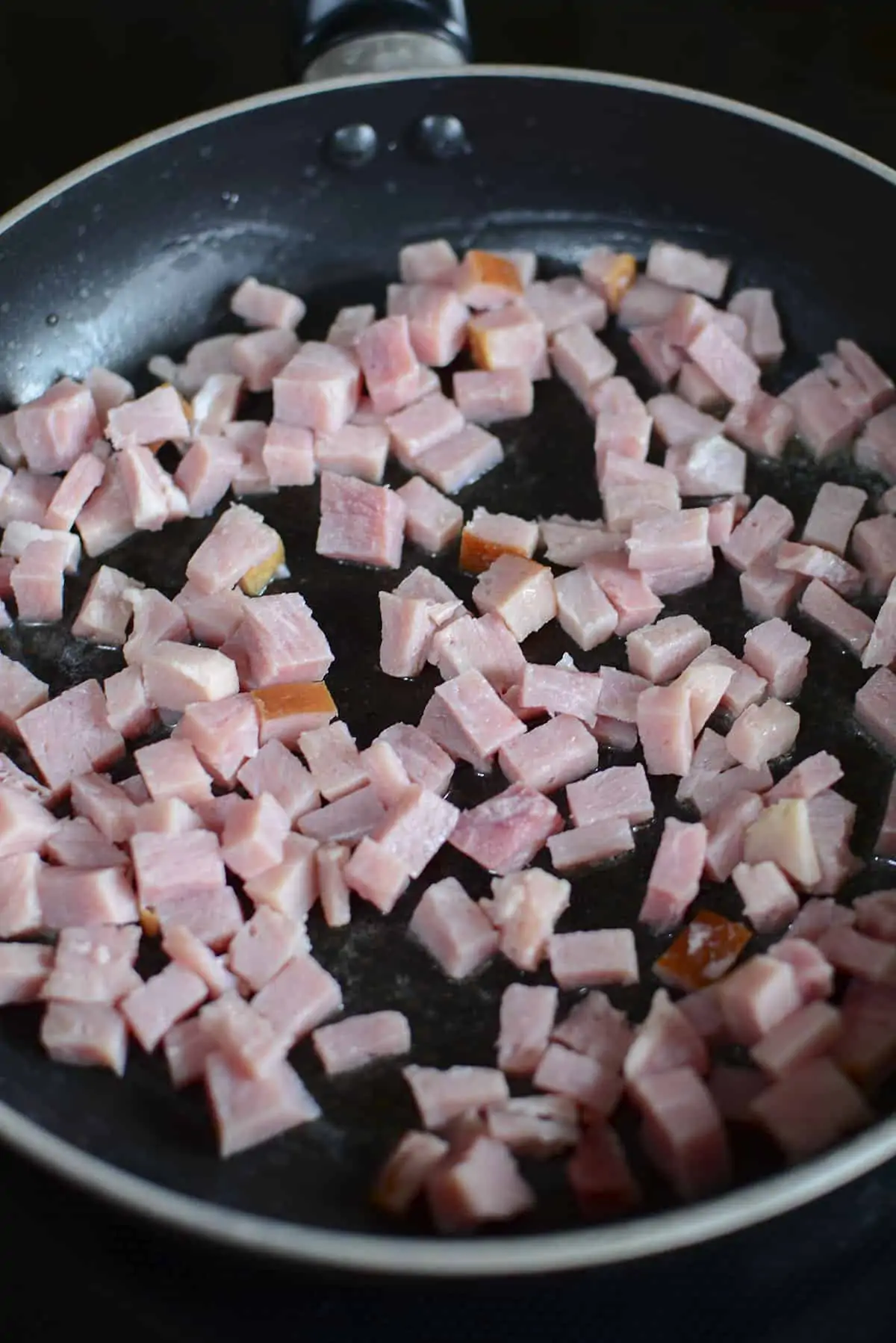Sauteing the diced ham in a skillet.
