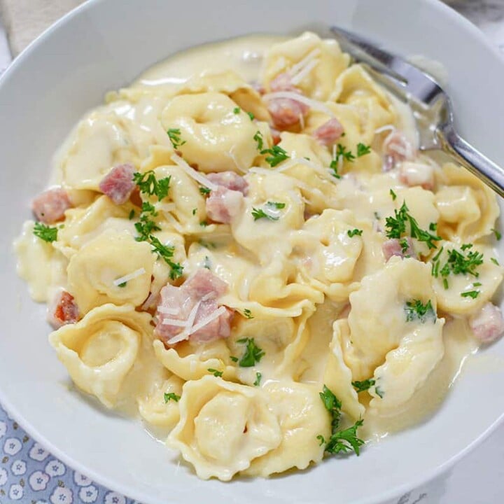 Creamy sauce with ham and cheese tortellini in a bowl.
