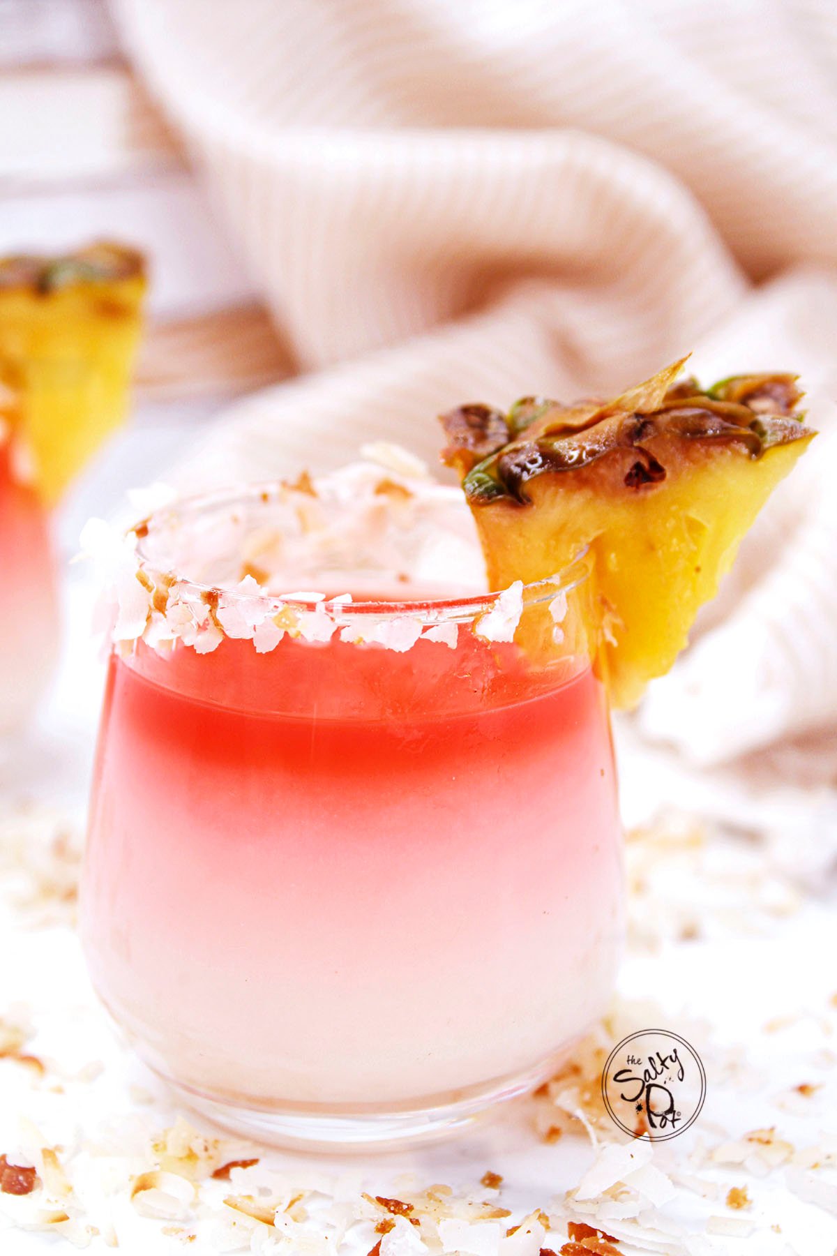 A shotglass with a mix of tropical flavors with coconut around the rim.