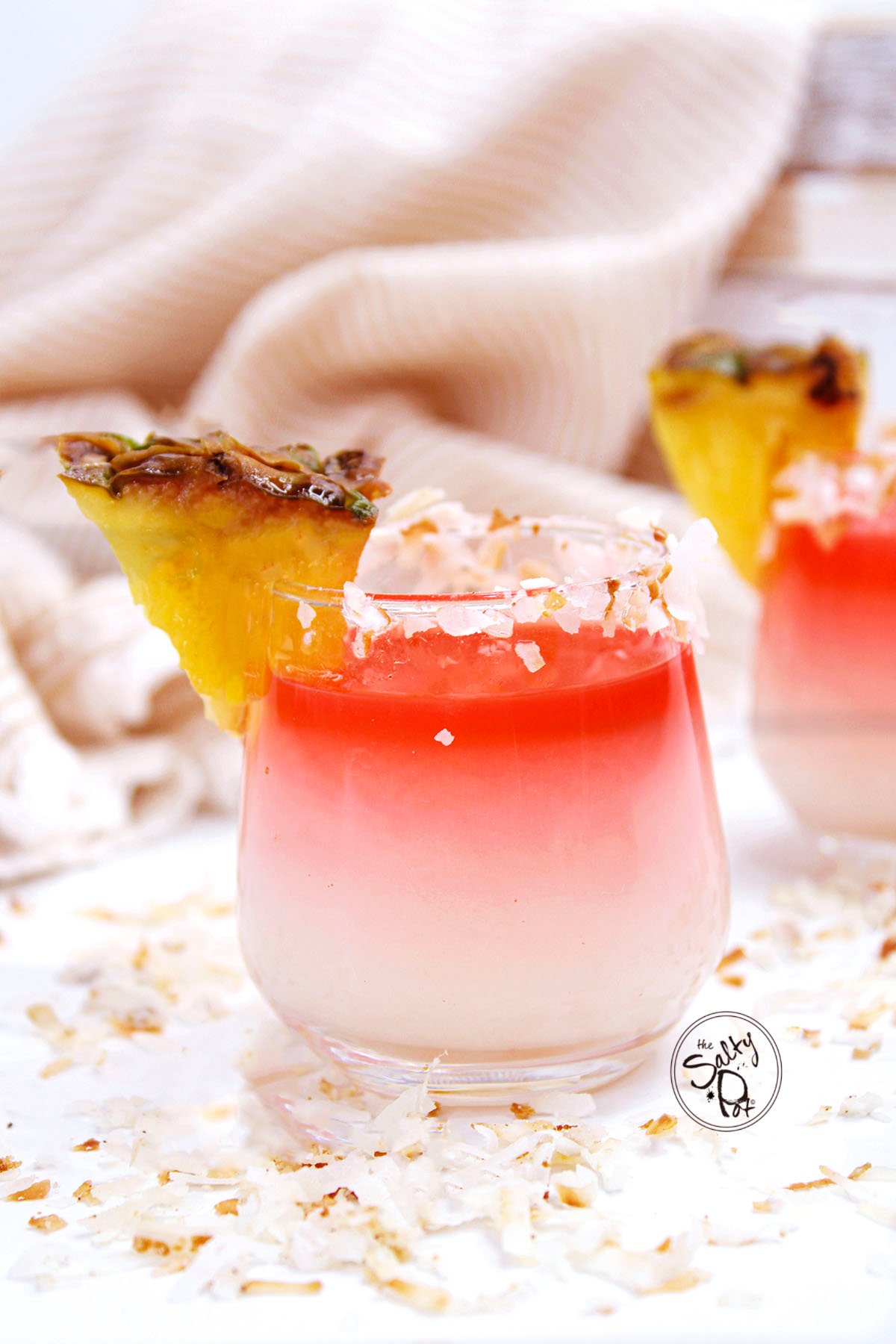 A pina colada shot with coconut and pineapple on the edge.