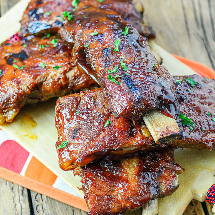 Oven Roasted Ribs piled on top of eachother on a wooden background.