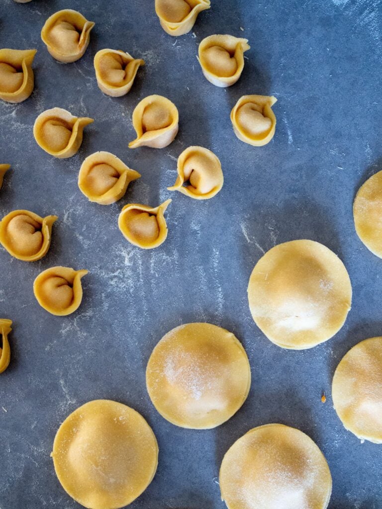 Ravioli and tortellini on a blue table.