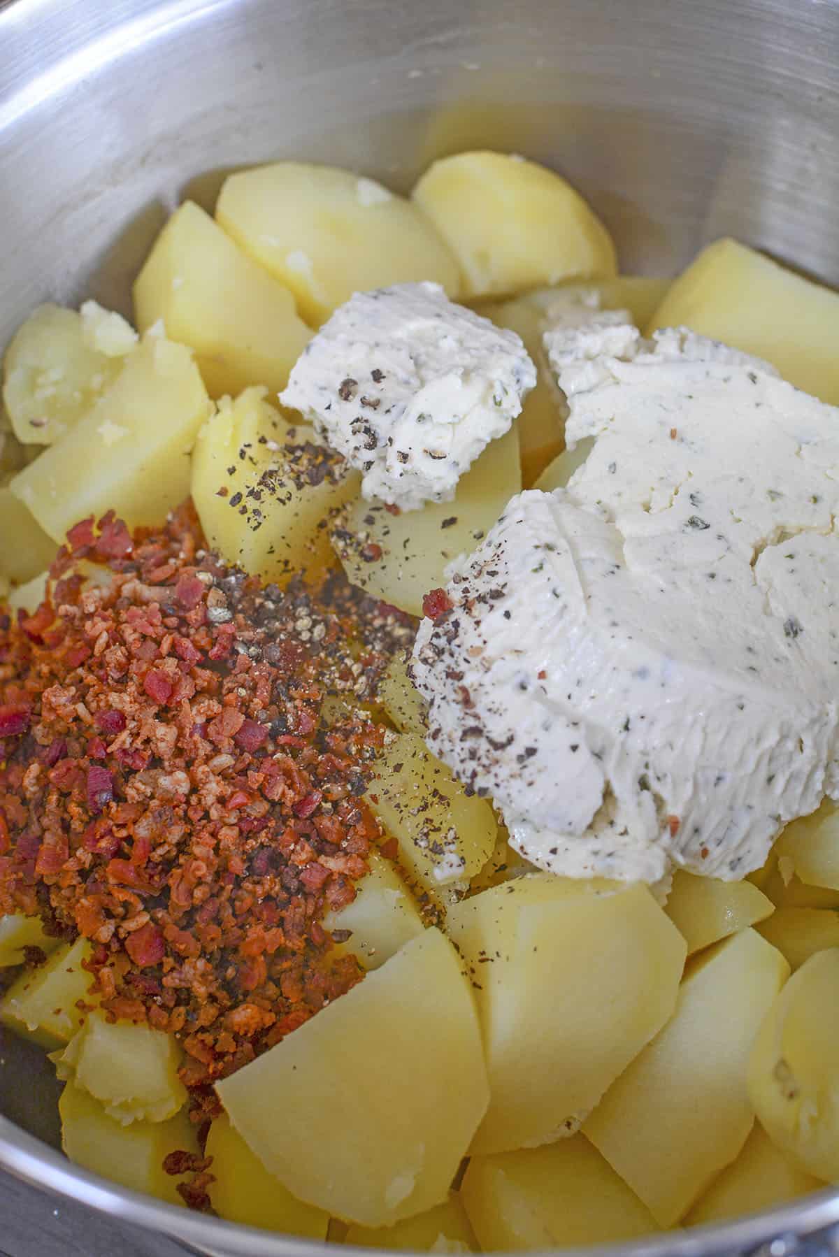 All the ingredients added to the bowl of boiled potatoes, ready to mash.