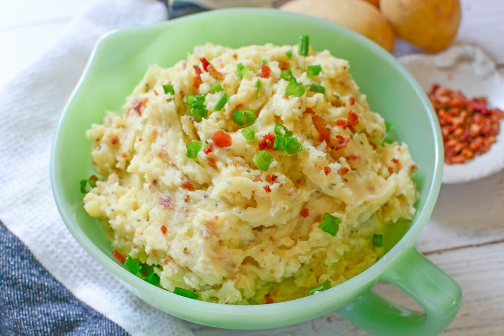 Mashed potatoes with Boursin Cheese in a green bowl.