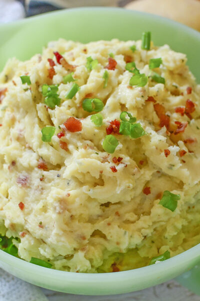 Mashed potatoes with Boursin Cheese in a green bowl.