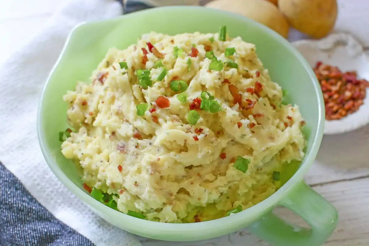 Mashed potatoes with Boursin Cheese in a green bowl.