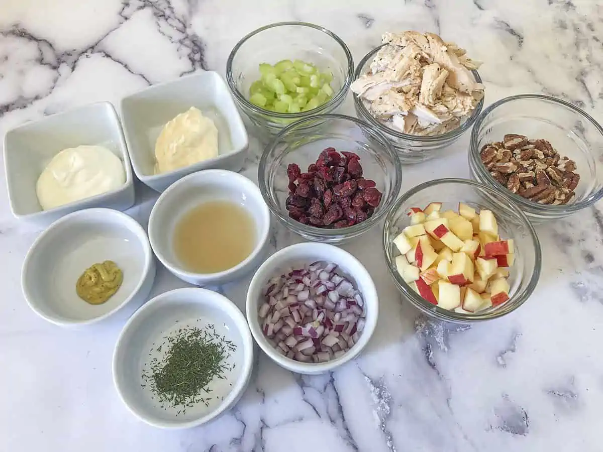 Ingredients for the salad in bowls, on a marble table surface.