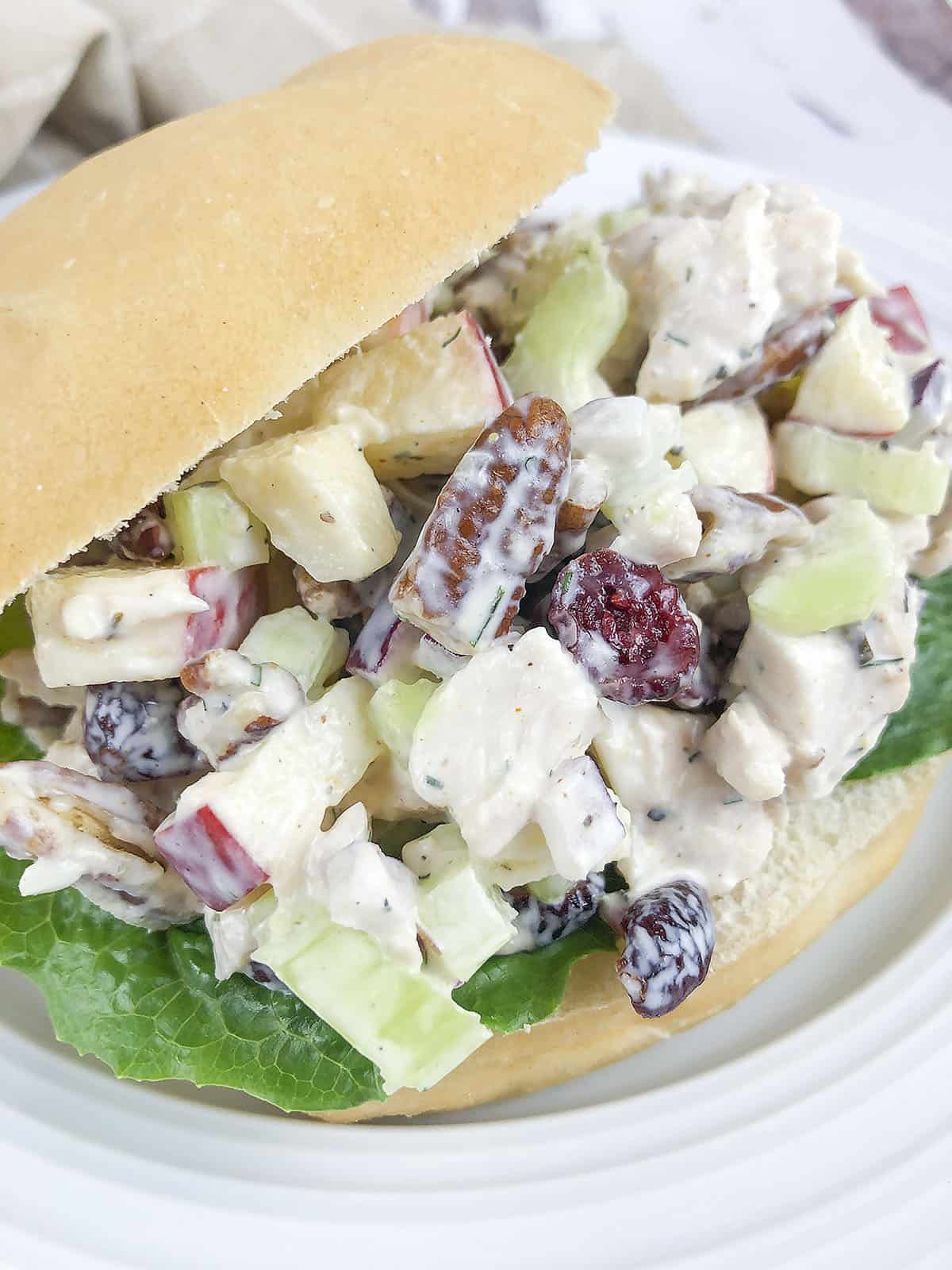 Chicken salad on a bun with lettuce underneath. 