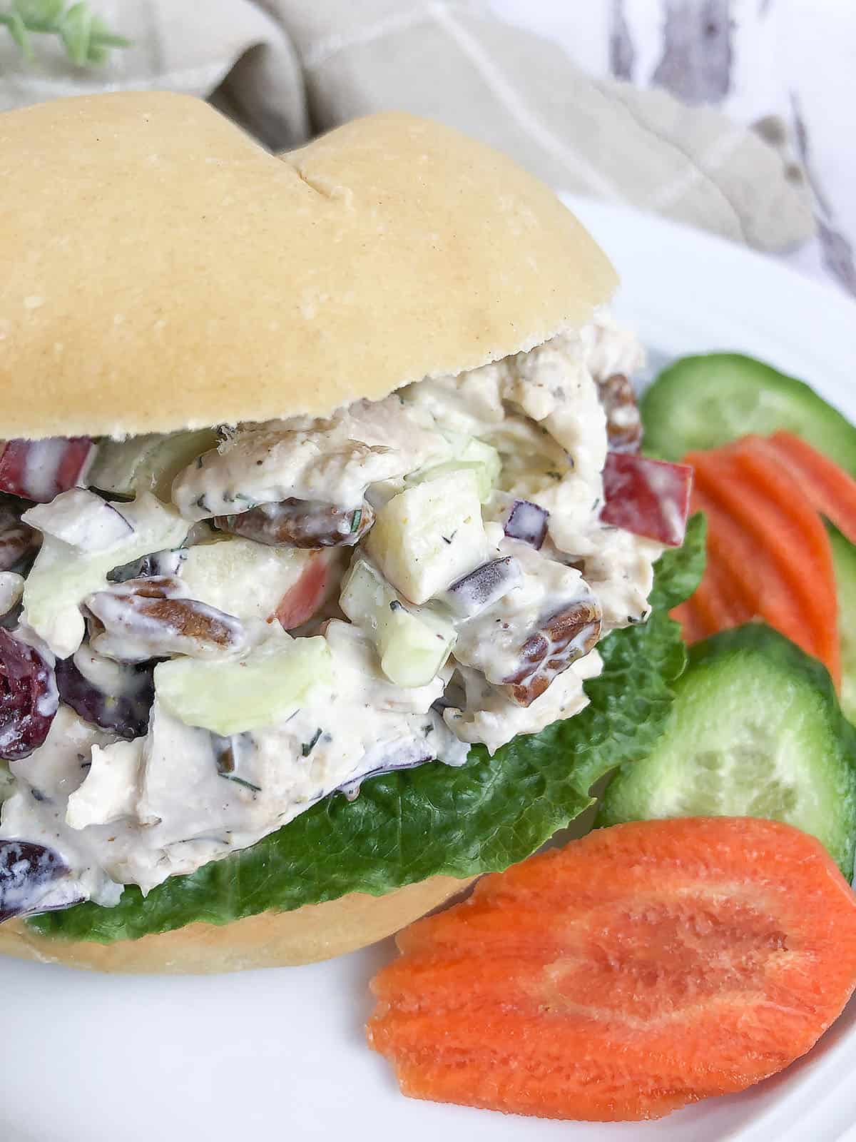 Chicken salad on a bun with vegetables.