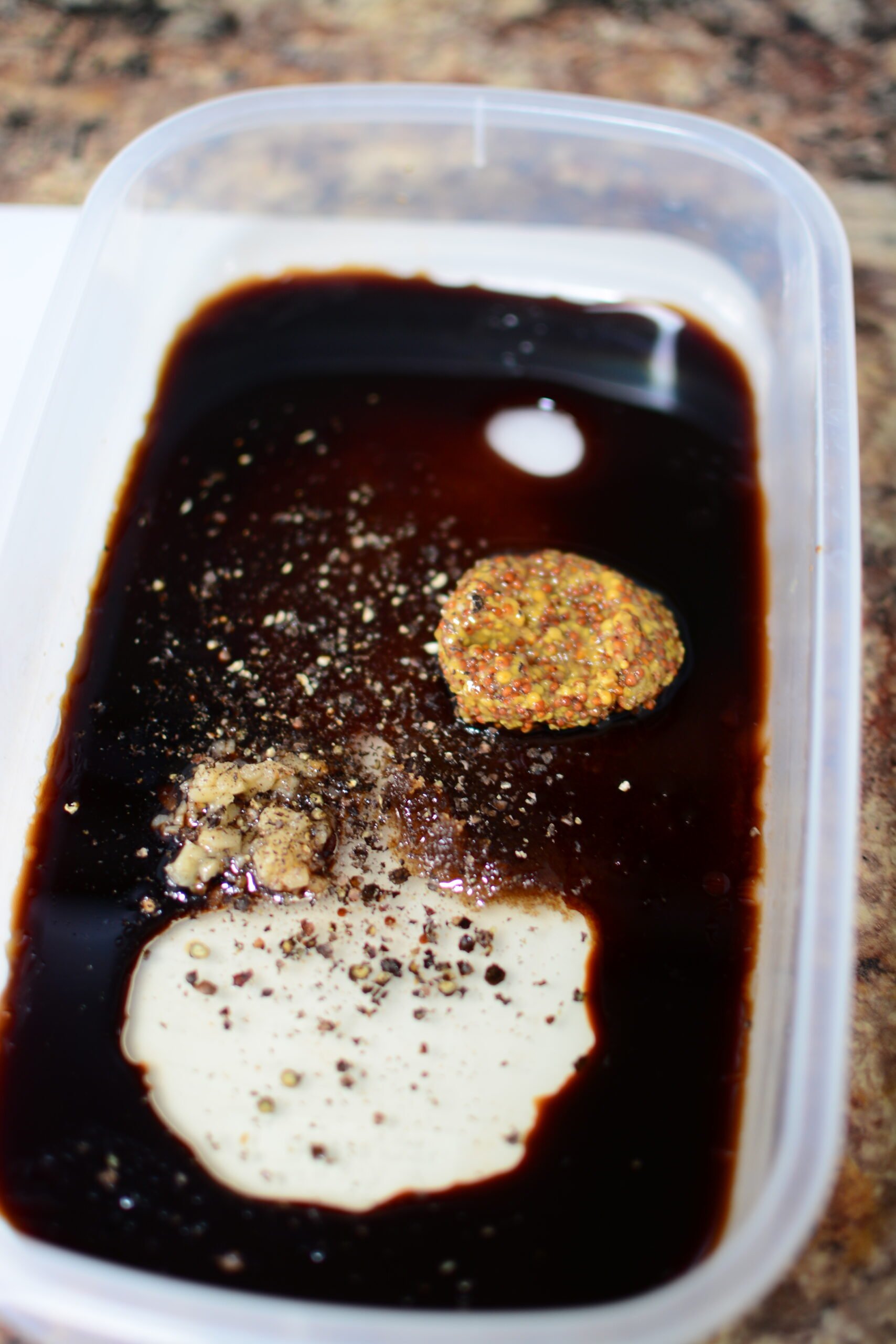 Ingredients unstirred in a container to make the balsamic marinade.