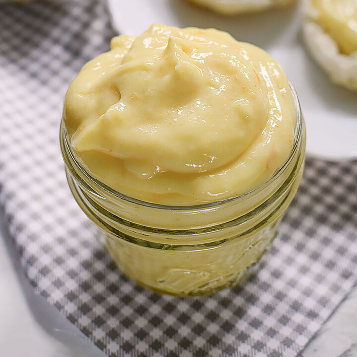 Lemon curd spread piled into a glass storage container.