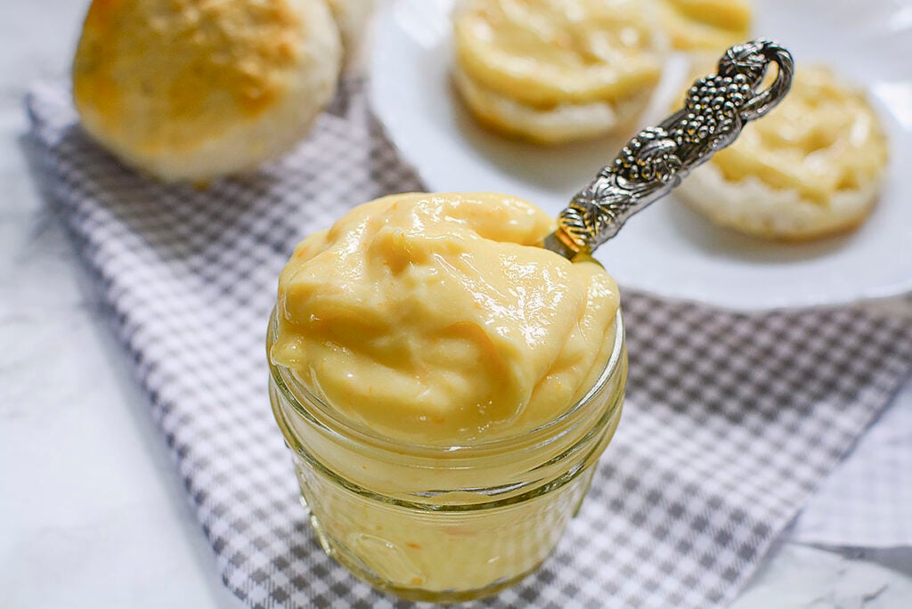 Lemon curd in a mason jar with a silver butter knife sticking out the top.