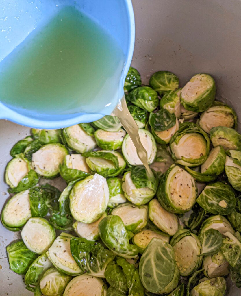 Broth is added to the sprouts. The broth is in a blue container.
