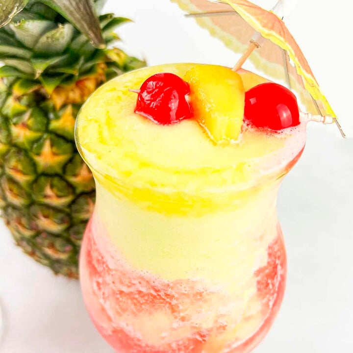 A glass with the pineapple slush filled to the rim. Cherries and pineapple for garnish.