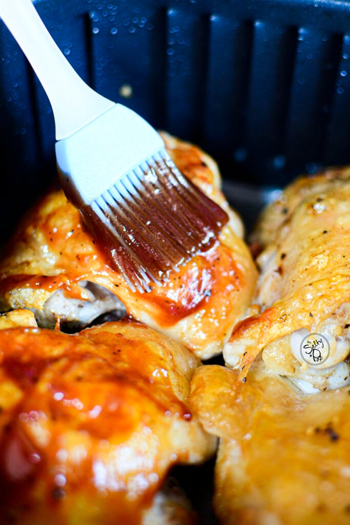 A blue silicon brush basting the tops of the chicken pieces. 