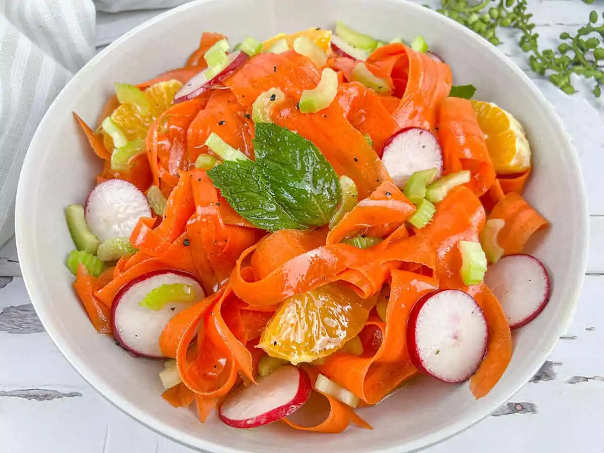 Shaved carrot salad in a white bowl.