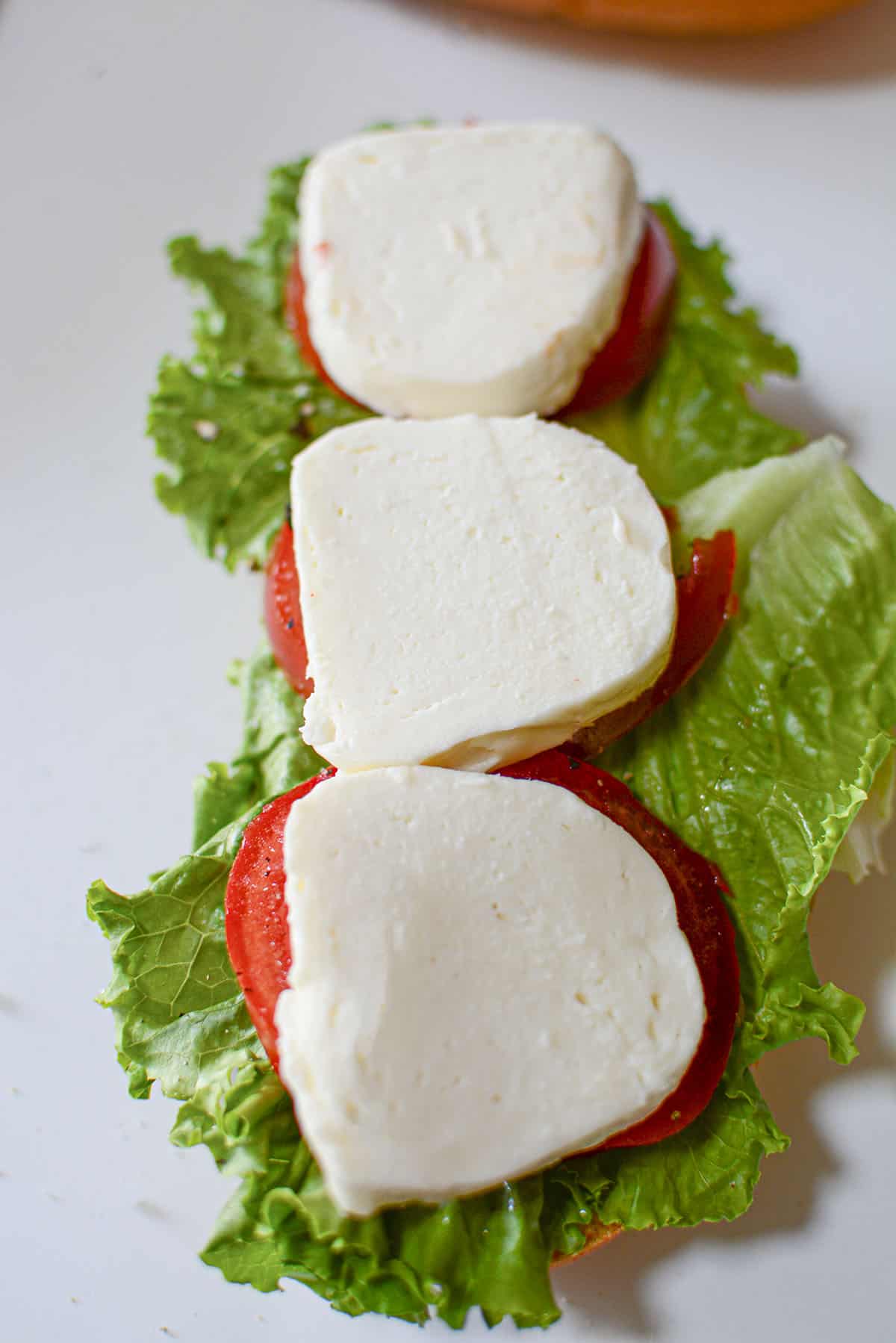 Sliced fresh mozzarella cheese is placed on top of the tomatoes for the sandwich. 