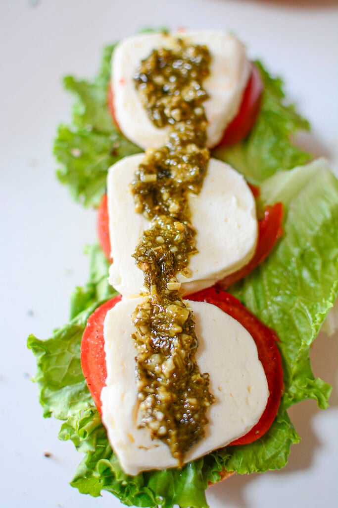 Pesto is put on top of the mozzarella cheese. 