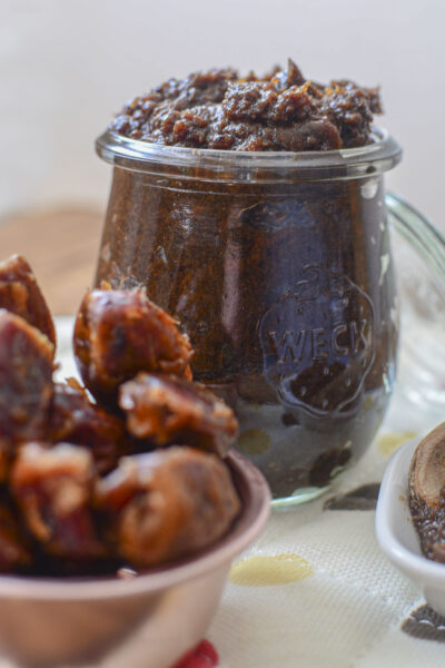 Date paste in a glass wreck jar with whole dates in the foreground.