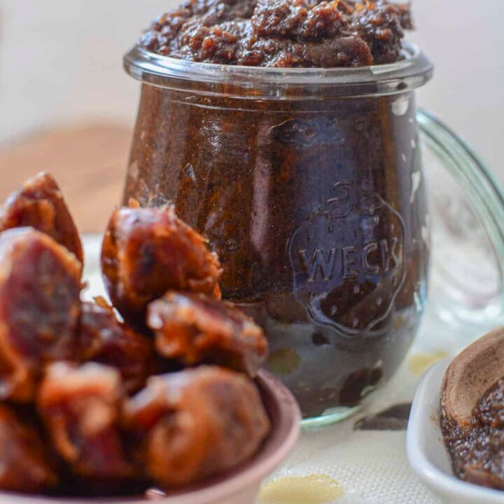 Date paste in a glass wreck jar with whole dates in the foreground.