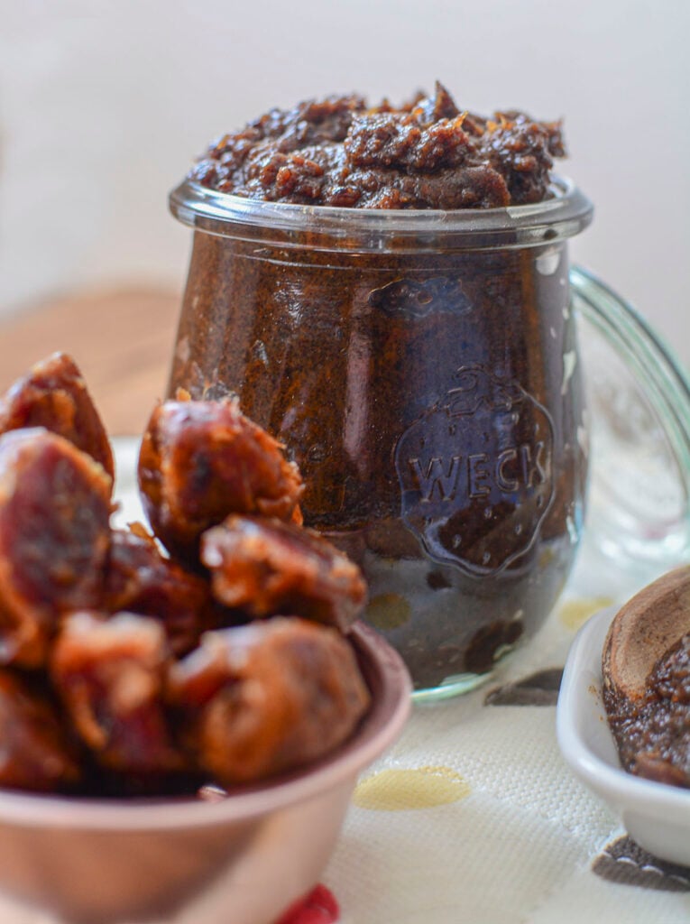 Date paste in a glass wreck jar with whole dates in the foreground.