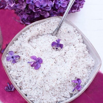 Lilac sugar in a bowl on a purple sloth with lilacs at the top.